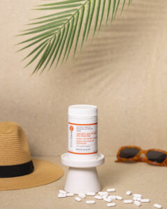 Niacinamide tablets with a hat, sunglasses and palm frond in background