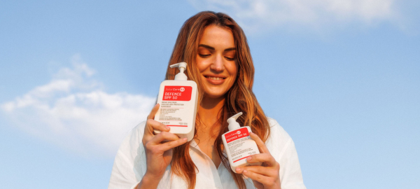 Woman holding both sizes of Defence SPF 50 with niacinamide by SolarCareB3