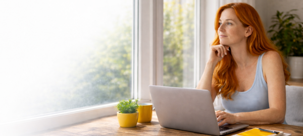 A woman working next to a bright window as light comes through.