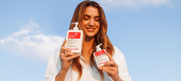 A woman holding two bottles of Defence SPF 50 with 5% niacinamide